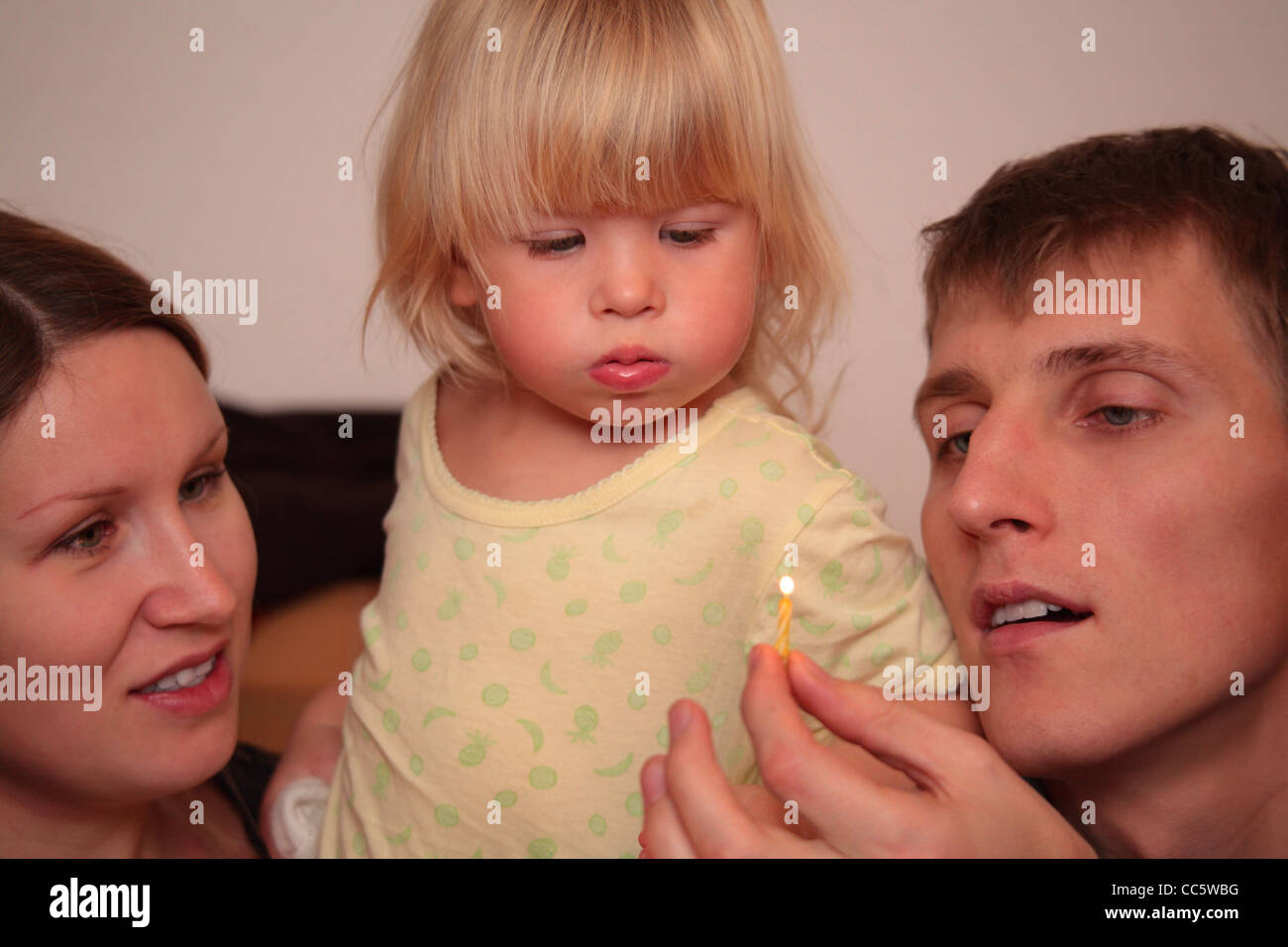 little girl looks on burning candle in father`s hand Stock Photo